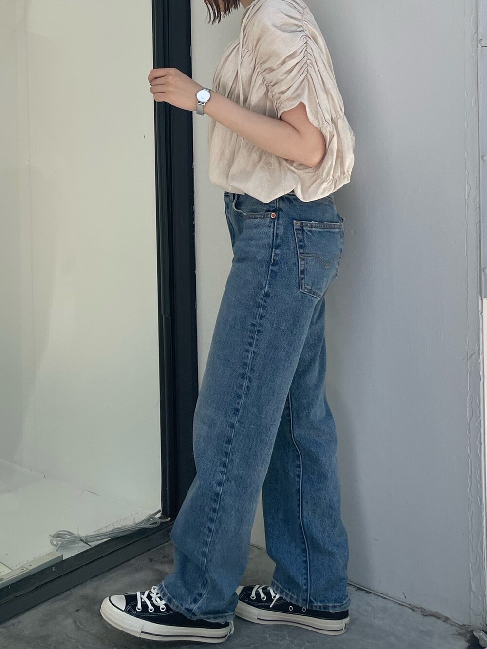 ホワイト系のシャツ/ブラウス、ブラック系のスニーカー、ブルー系のデニムパンツを着用したレディースの夏コーディネートの5枚目の写真