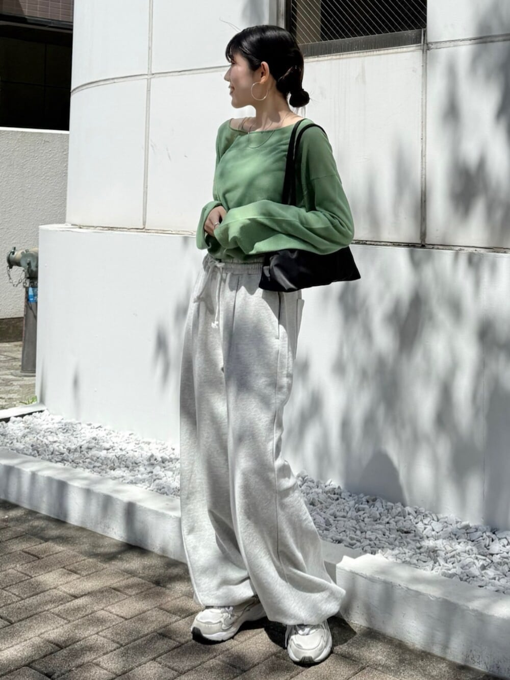 グレー系のスウェットパンツ、ブラック系のハンドバッグ、グリーン系のニット/セーターを着用したレディースの春コーディネートの2枚目の写真