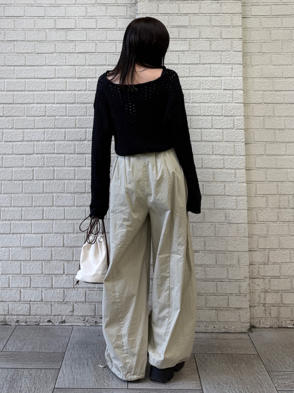 ベージュ系のその他パンツ、ホワイト系のショルダーバッグ、ブラック系のニット/セーターを着用したレディースの春コーディネートの6枚目の写真
