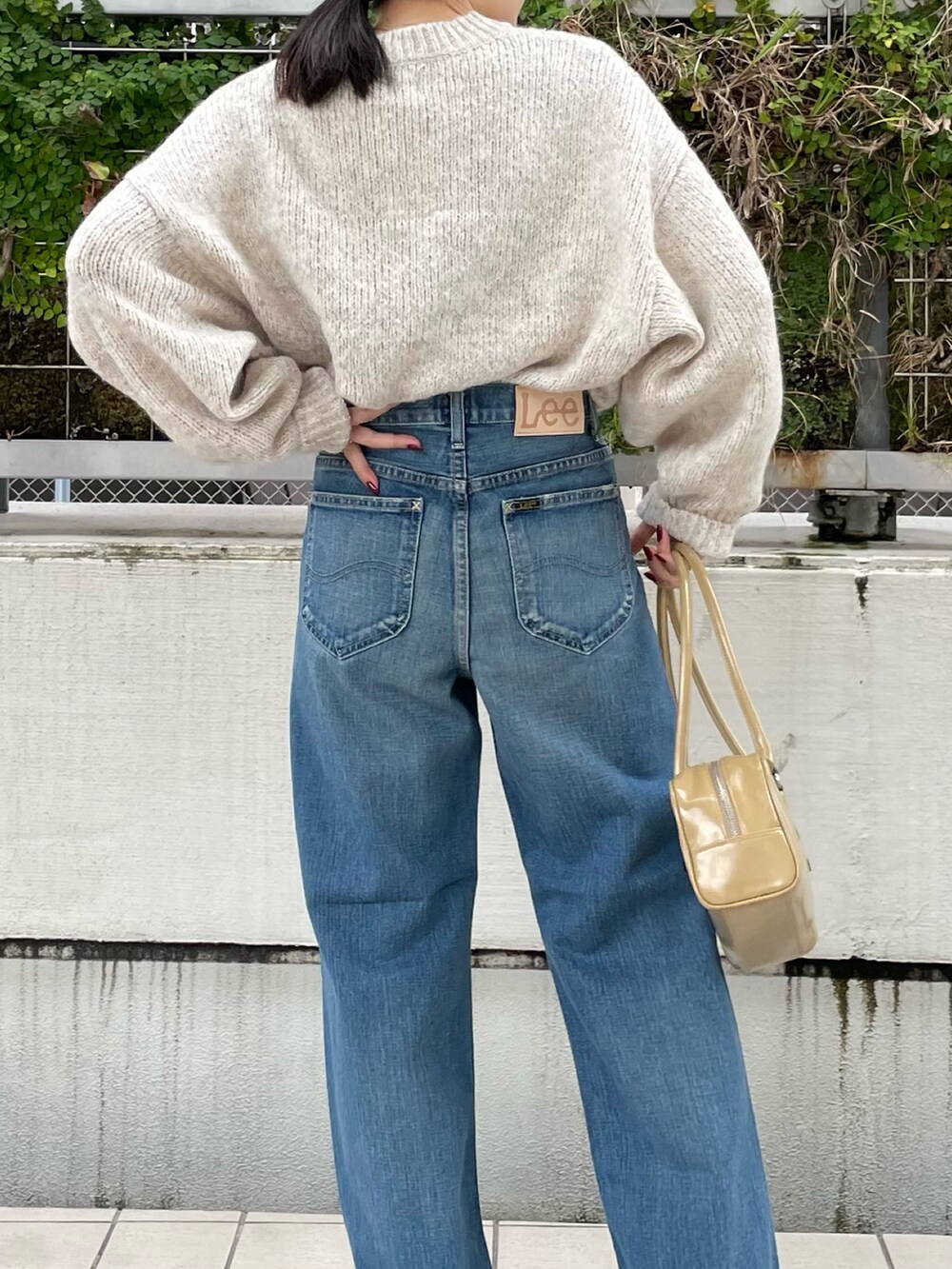 ブルー系のデニムパンツ、ブラウン系のブーツ、ベージュ系のハンドバッグを着用したレディースの秋コーディネートの8枚目の写真