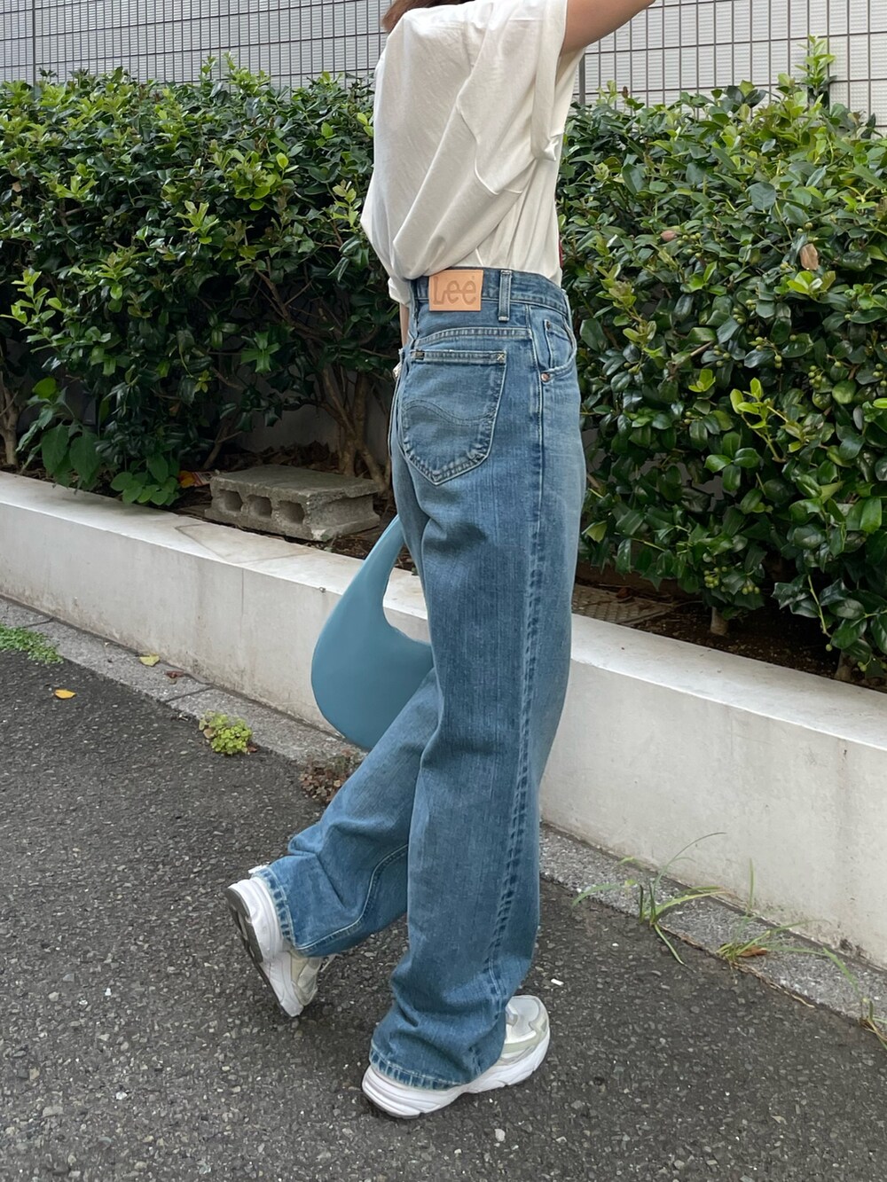 ホワイト系のTシャツ/カットソー、ブルー系のハンドバッグ、ブルー系のデニムパンツを着用したレディースの夏コーディネートの5枚目の写真