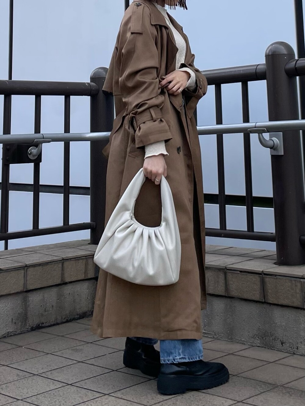 ホワイト系のハンドバッグ、ホワイト系のTシャツ/カットソー、ブルー系のデニムパンツを着用したレディースの冬コーディネートの2枚目の写真