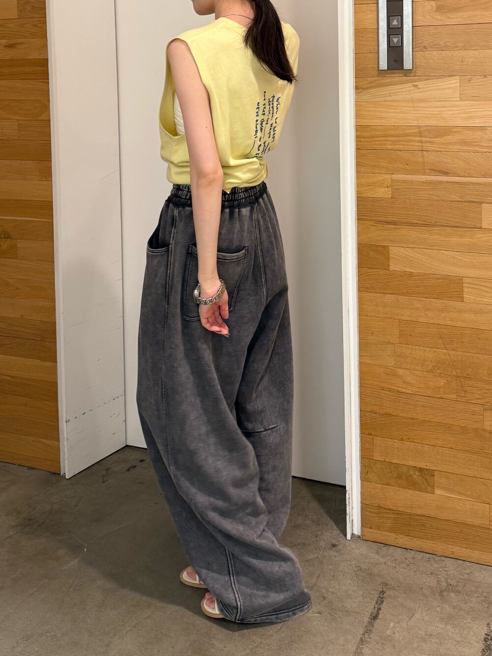 グレー系のスウェットパンツ、イエロー系のタンクトップ、ホワイト系のサンダルを着用したレディースの夏コーディネートの5枚目の写真
