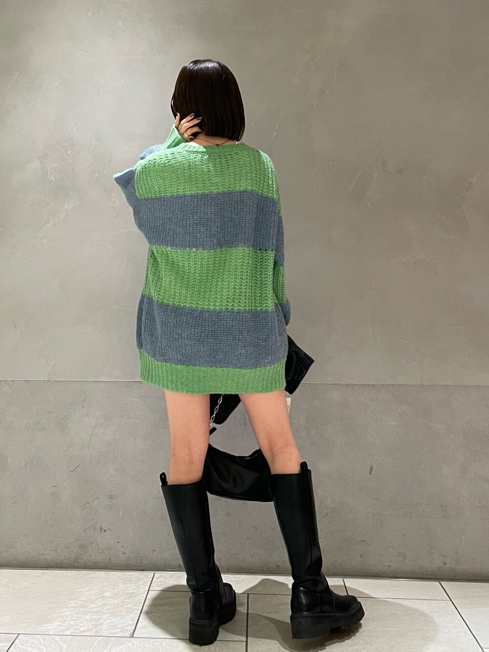 グリーン系のニット/セーター、ホワイト系のTシャツ/カットソー、グレー系のマフラーを着用したレディースの冬コーディネートの7枚目の写真