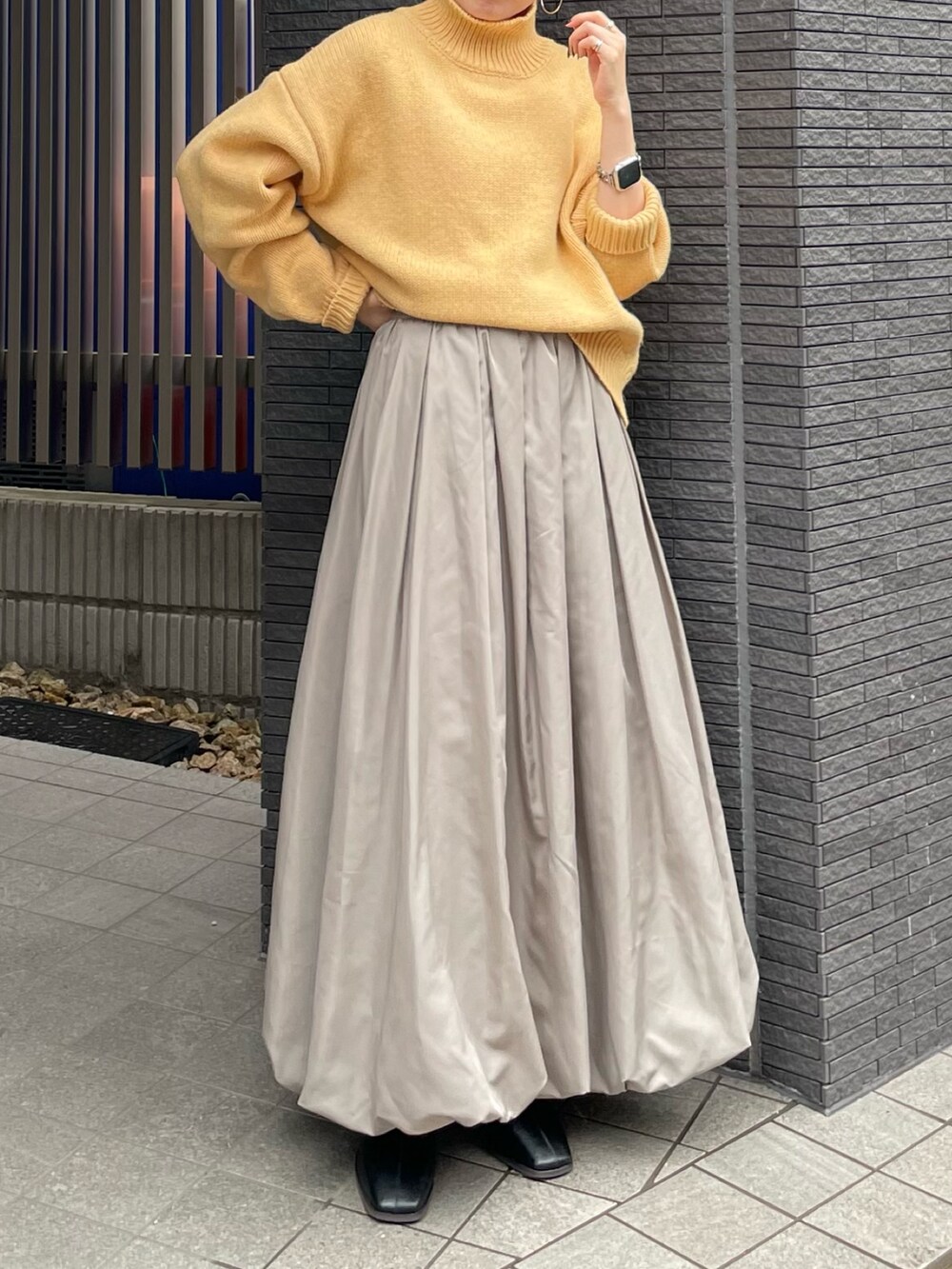 ブラック系のブーツ、イエロー系のニット/セーター、グレー系のスカートを着用したレディースの冬コーディネートの6枚目の写真