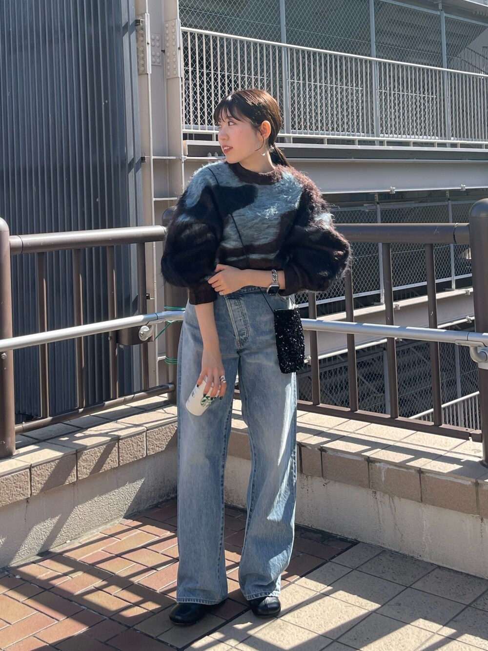 ブラック系のブーツ、ブラウン系のニット/セーター、ブルー系のデニムパンツを着用したレディースの秋コーディネートの6枚目の写真