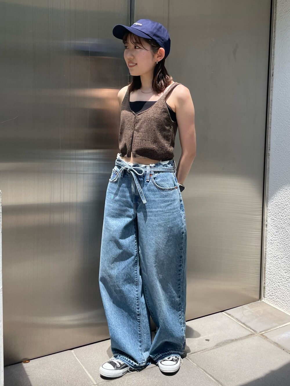 ブラウン系のベスト、ブルー系のデニムパンツ、ブルー系のキャップを着用したレディースの夏コーディネートの6枚目の写真