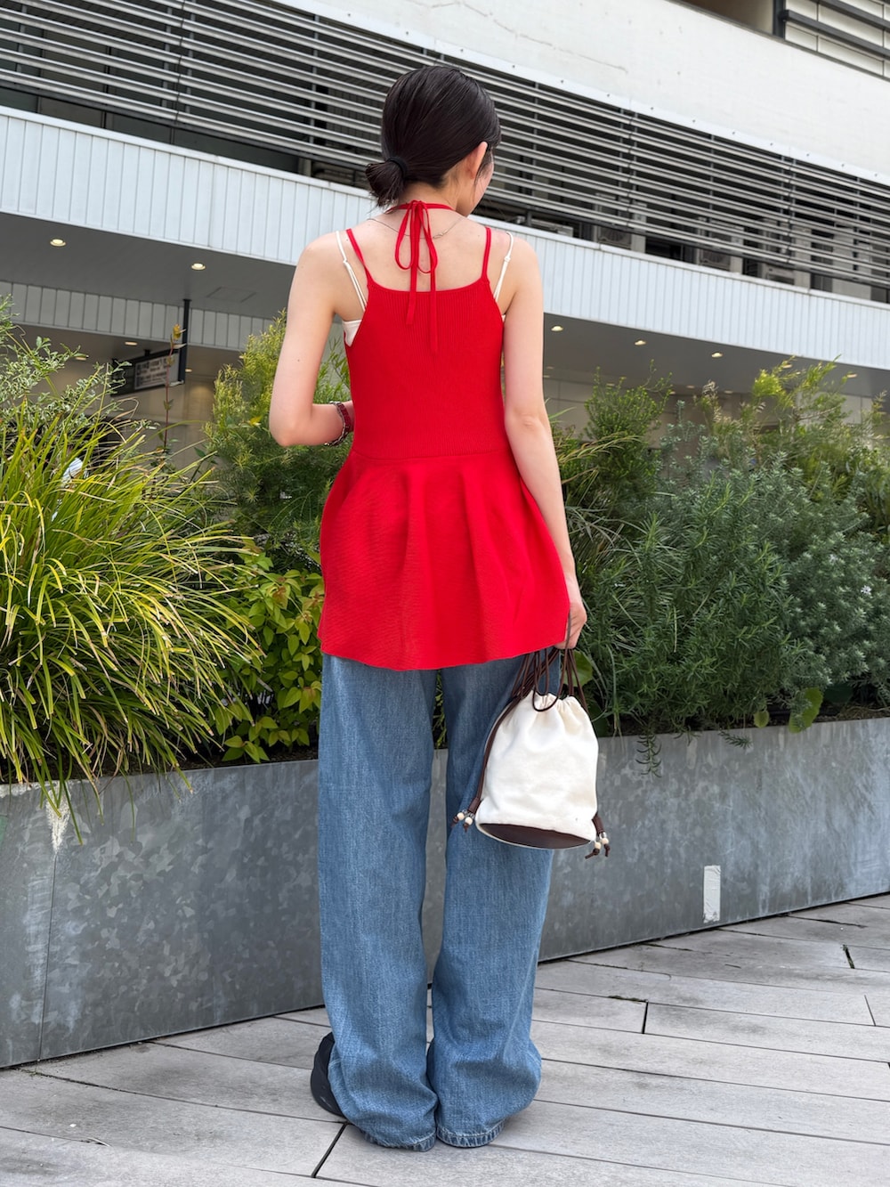 レッド系のキャミソール、ブルー系のデニムパンツ、ブラック系のブーツを着用したレディースの春コーディネートの5枚目の写真