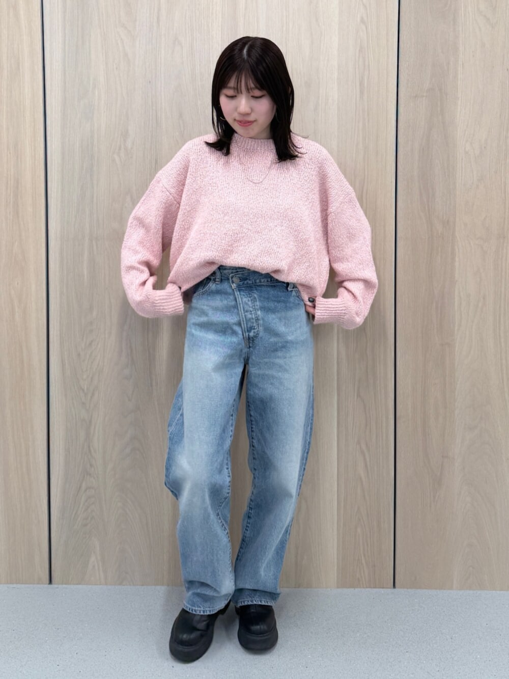 ブルー系のデニムパンツ、ピンク系のニット/セーター、ブラック系のブーツを着用したレディースの冬コーディネートの2枚目の写真