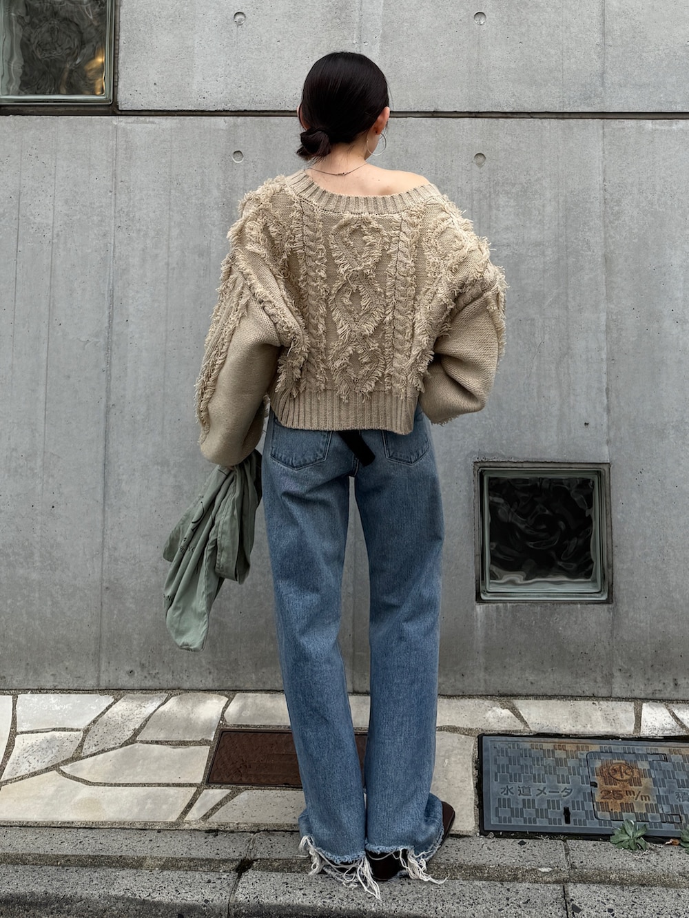 ブルー系のデニムパンツ、グリーン系のトートバッグ、ブラウン系のブーツを着用したレディースの秋コーディネートの3枚目の写真