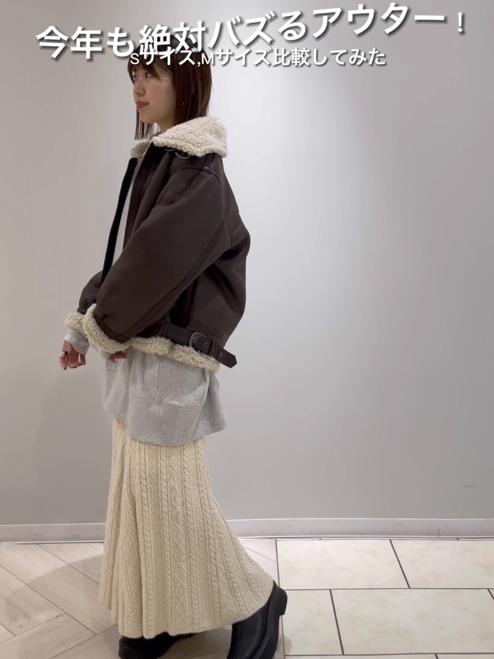 ブラウン系のムートンコート、グレー系のスウェット、ホワイト系のスカートを着用したレディースの秋コーディネートの2枚目の写真