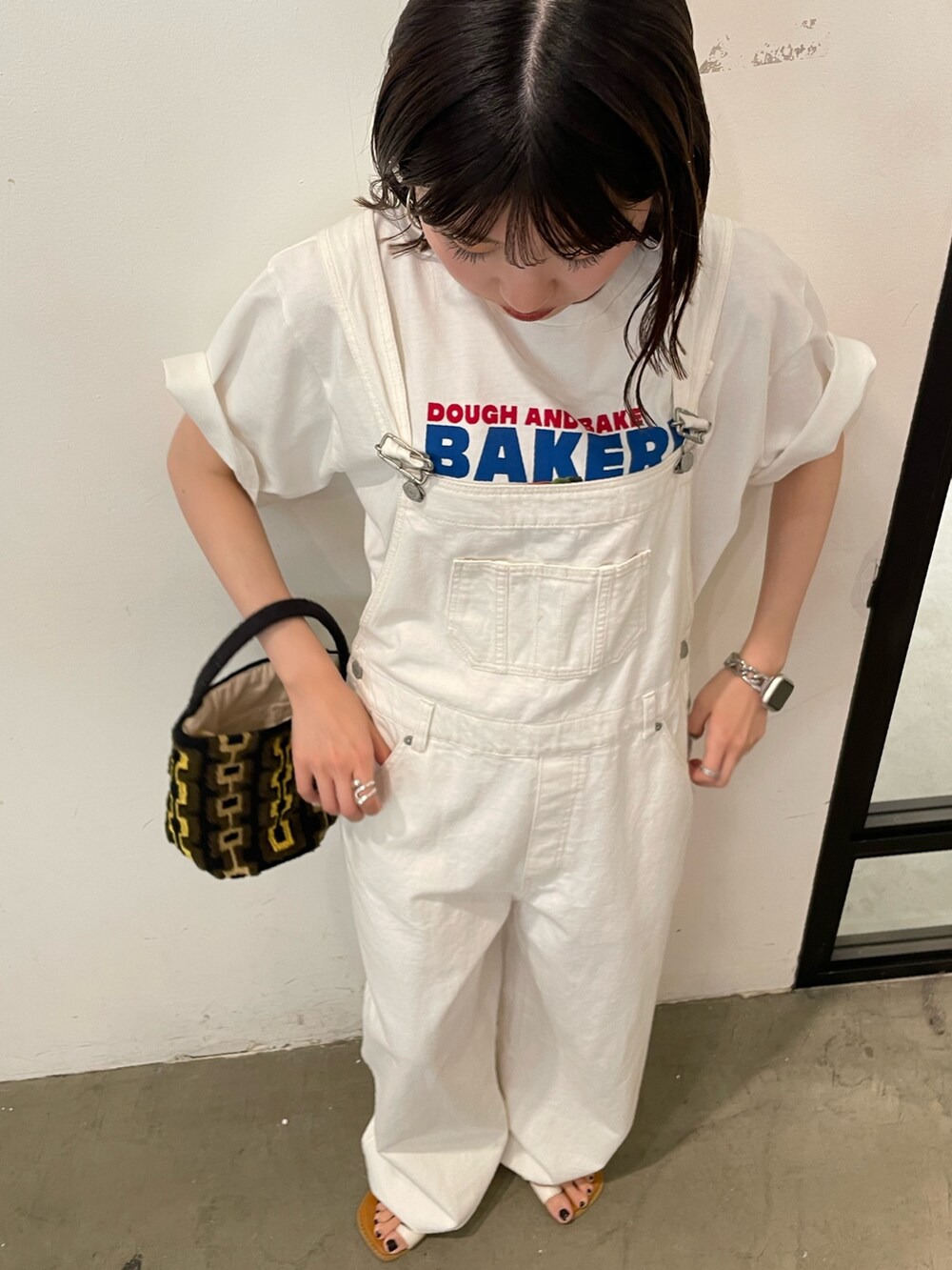 ホワイト系のサンダル、ホワイト系のTシャツ/カットソー、ブラウン系のハンドバッグを着用したレディースの春コーディネートの4枚目の写真