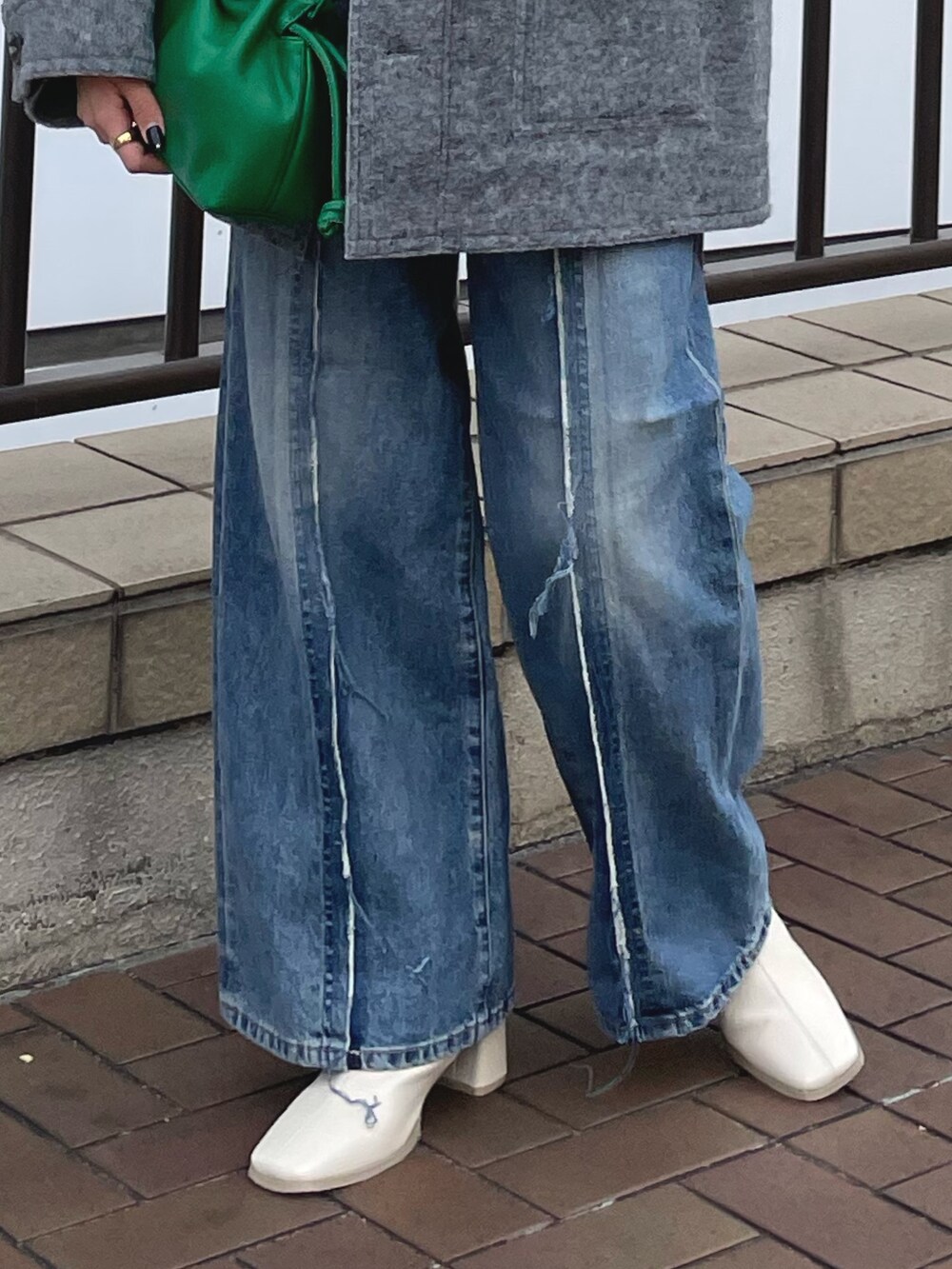 ブルー系のデニムパンツ、ホワイト系のブーツ、グリーン系のクラッチバッグを着用したレディースの秋コーディネートの8枚目の写真