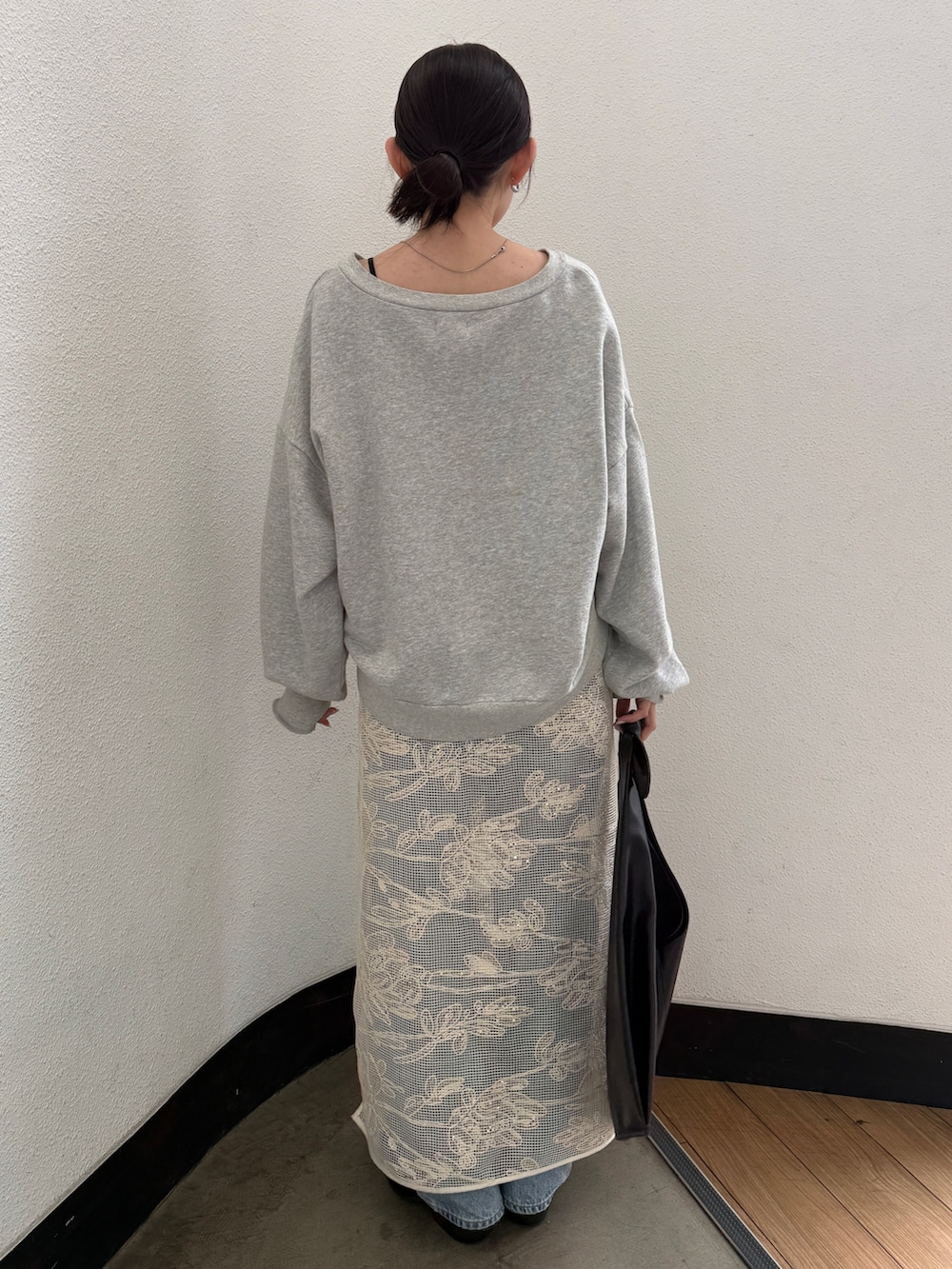 ブラック系のハンドバッグ、ブラック系のブーツ、ブルー系のデニムパンツを着用したレディースの春コーディネートの6枚目の写真