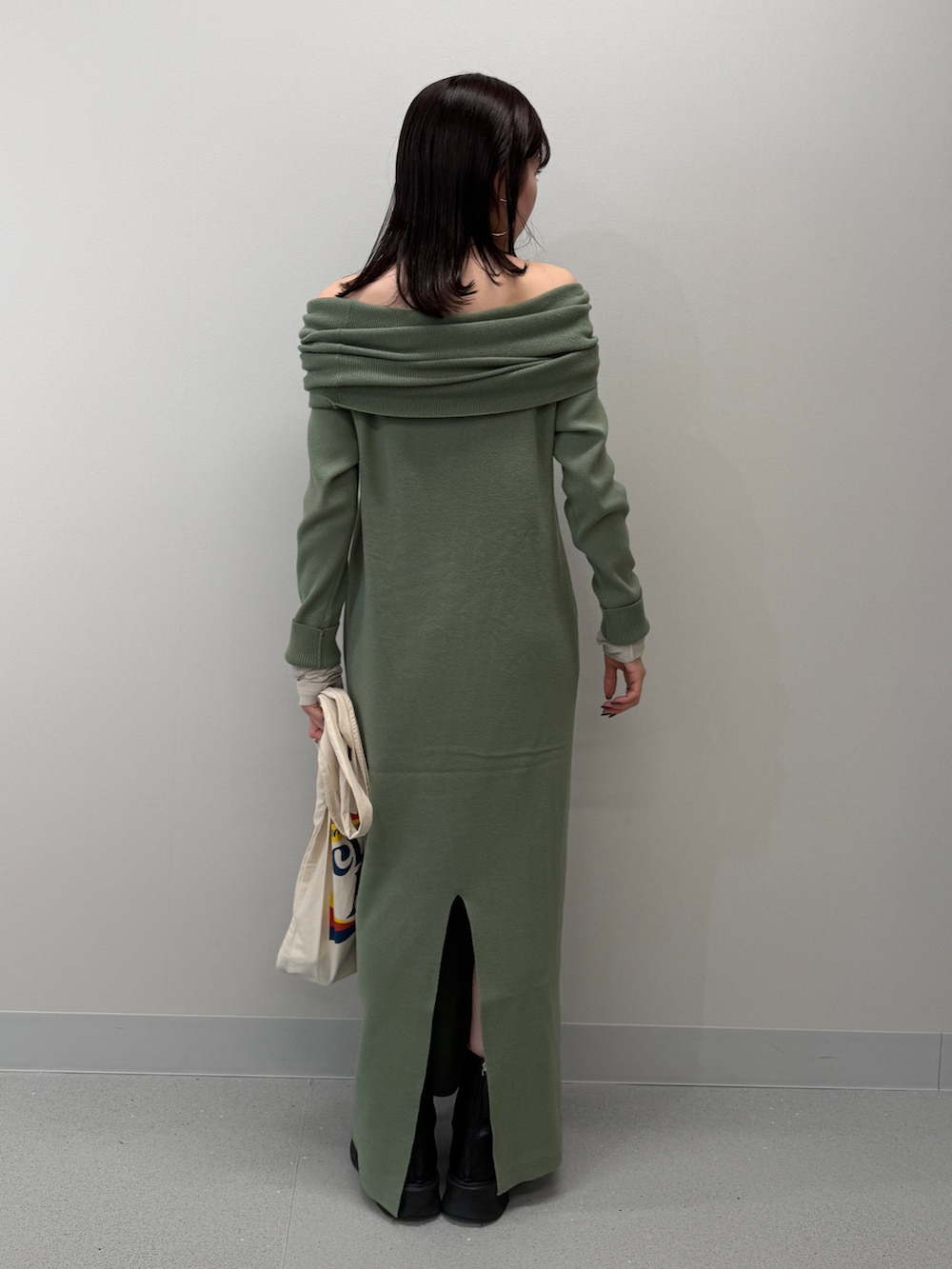 ホワイト系のトートバッグ、ブラック系のブーツ、グリーン系のワンピースを着用したレディースの冬コーディネートの4枚目の写真