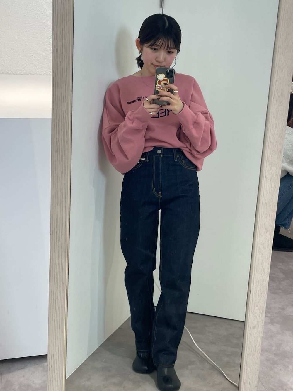 ブラック系のブーツ、ピンク系のスウェット、ブルー系のデニムパンツを着用したレディースの冬コーディネートの4枚目の写真