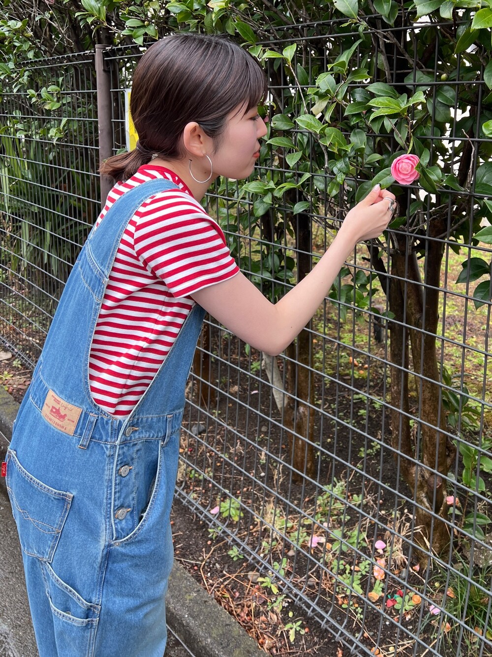 ブラック系のサンダル、ブルー系のつなぎ/オールインワン、レッド系のTシャツ/カットソーを着用したレディースの春コーディネートの2枚目の写真