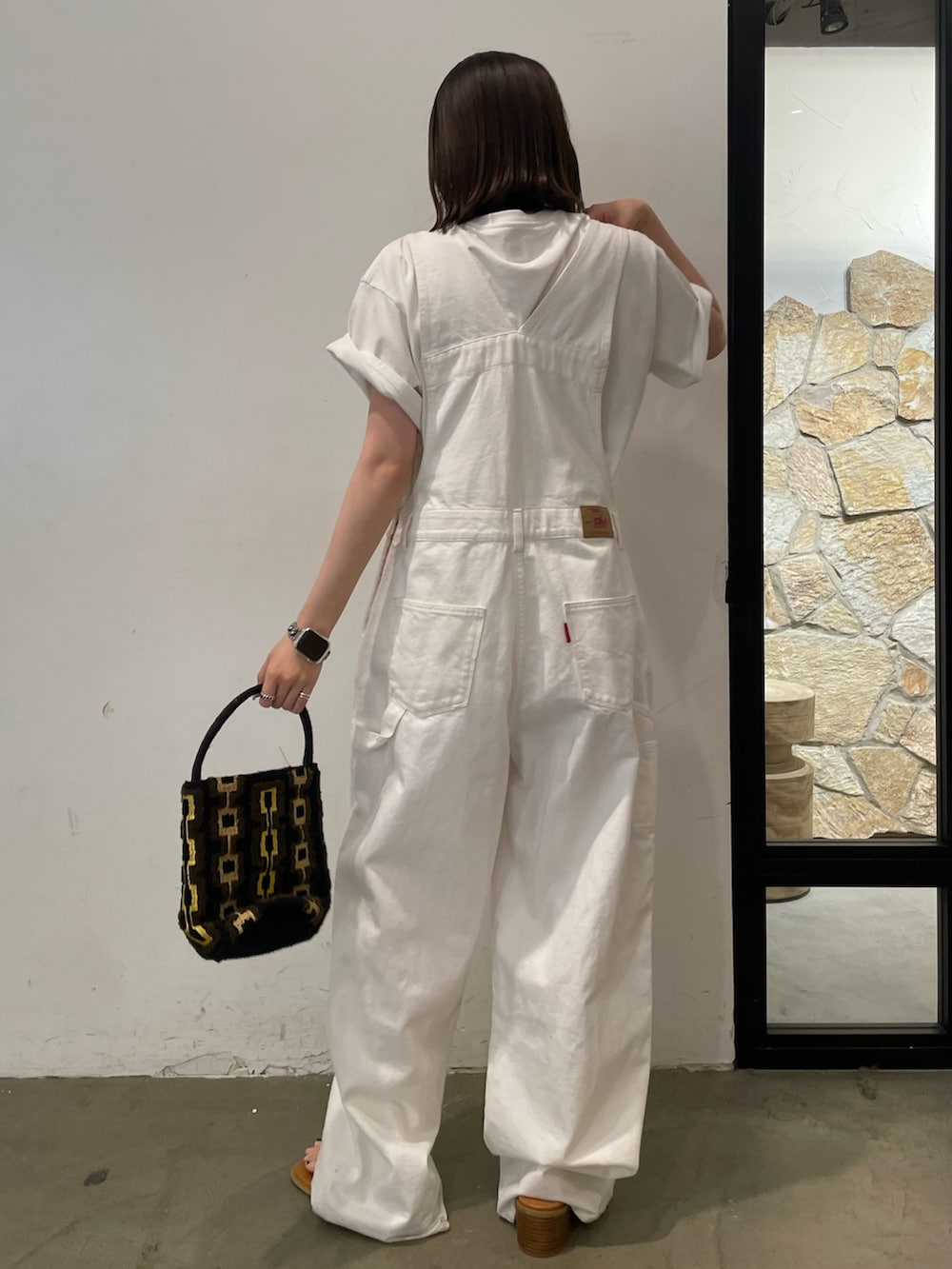 ホワイト系のサンダル、ホワイト系のTシャツ/カットソー、ブラウン系のハンドバッグを着用したレディースの春コーディネートの5枚目の写真