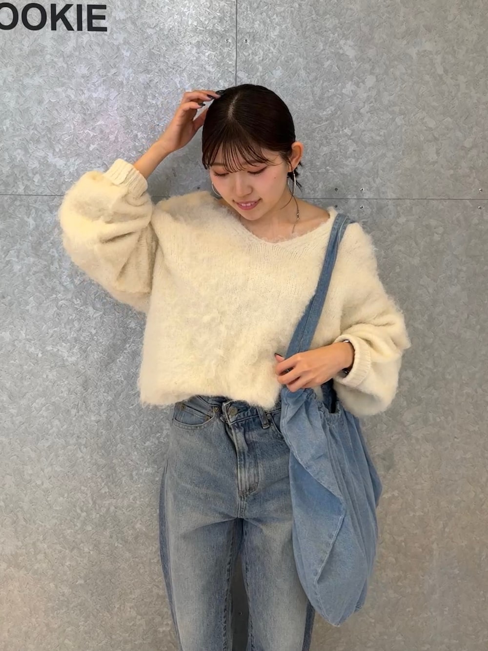 ブルー系のデニムパンツ、ブラウン系のハンドバッグ、ホワイト系のニット/セーターを着用したレディースの秋コーディネートの3枚目の写真