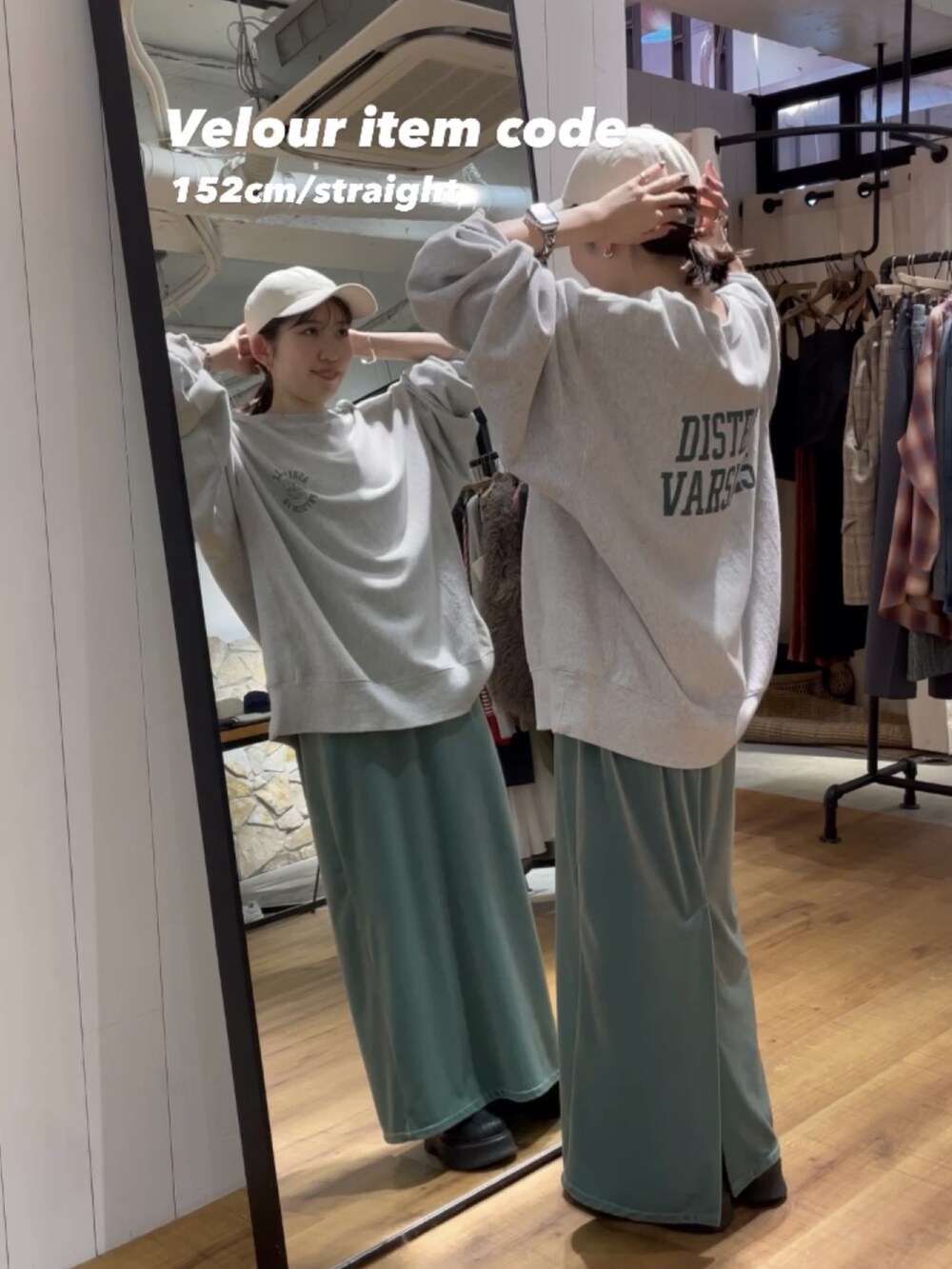 グリーン系のワンピース、ブラック系のブーツ、グレー系のスウェットを着用したレディースの秋コーディネートの2枚目の写真