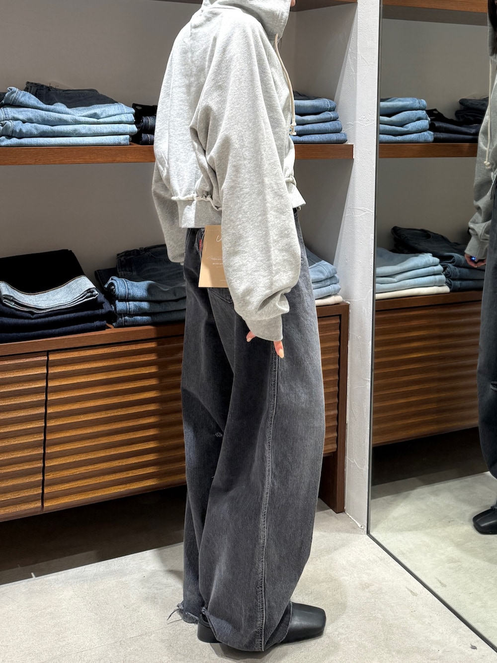 ブラック系のサンダル、グレー系のパーカー、ブラック系のデニムパンツを着用したレディースの春コーディネートの7枚目の写真