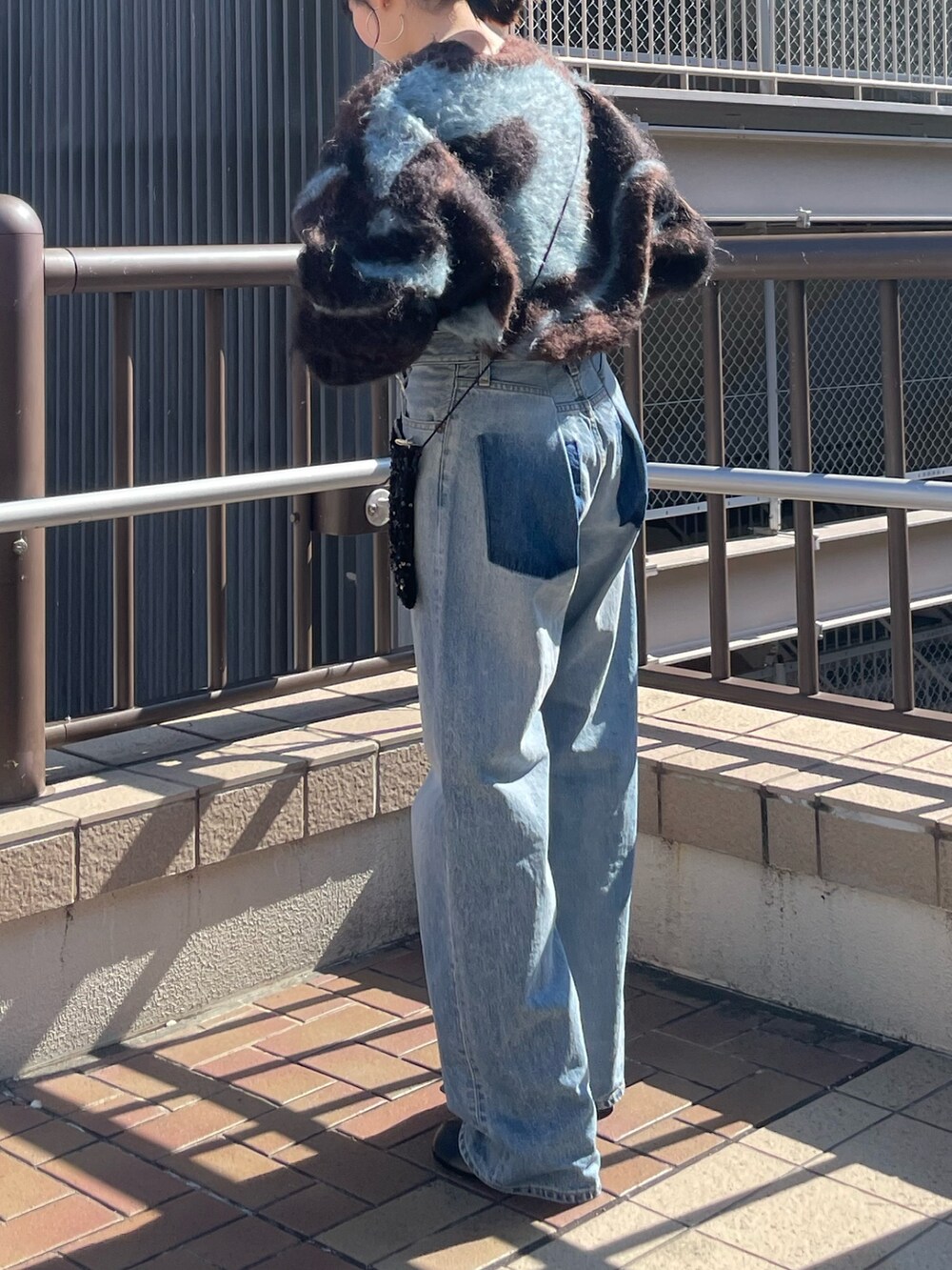 ブラック系のブーツ、ブラウン系のニット/セーター、ブルー系のデニムパンツを着用したレディースの秋コーディネートの5枚目の写真
