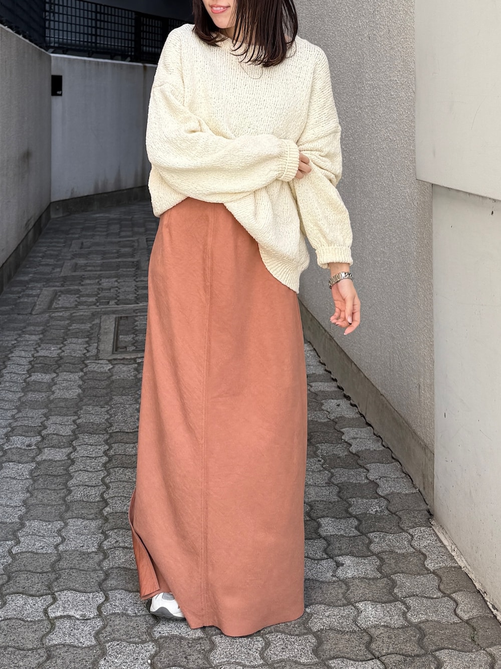 オレンジ系のスカート、ホワイト系のニット/セーターを着用したレディースの冬コーディネートの2枚目の写真
