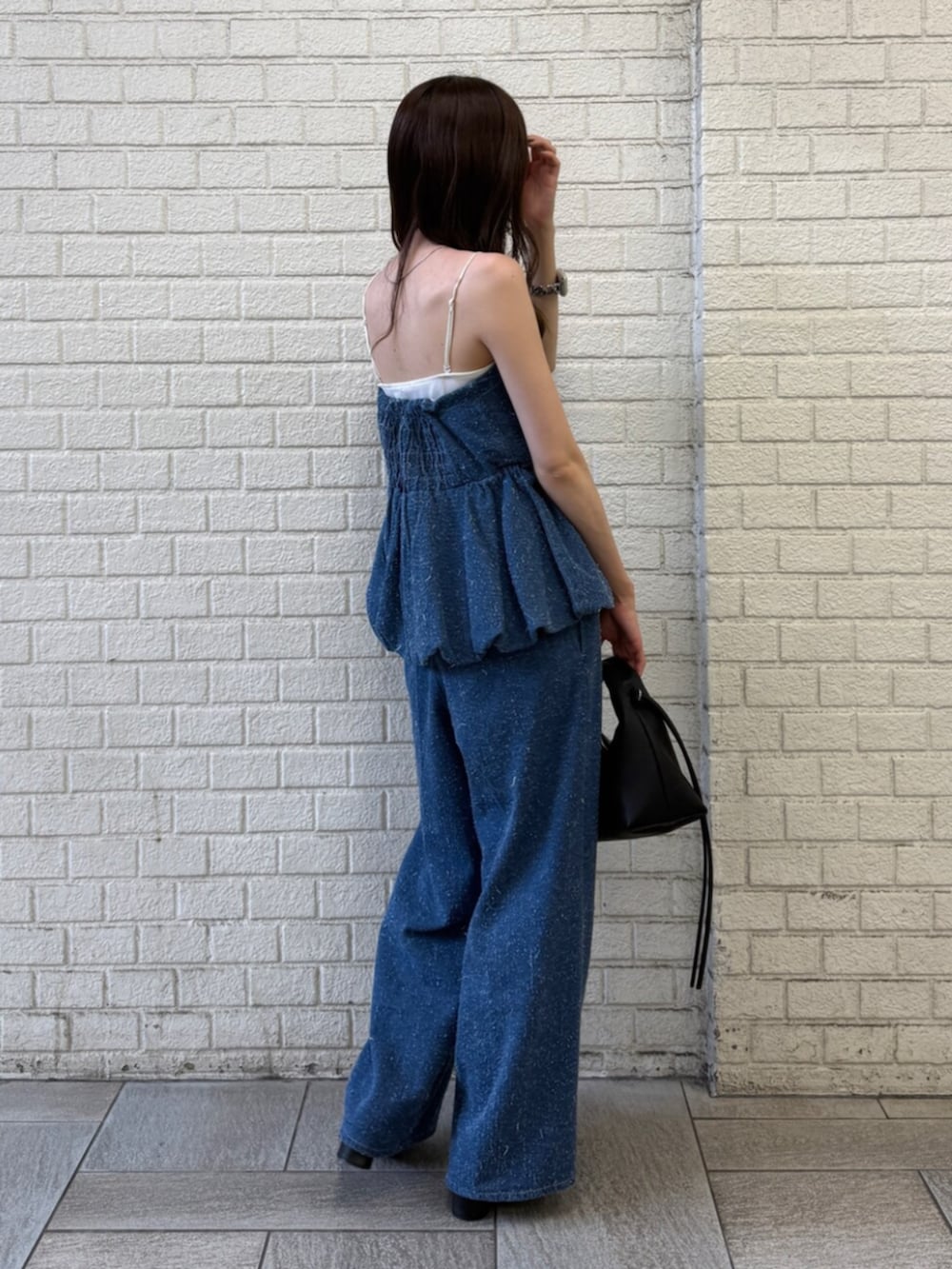 ブルー系のチューブトップ、ブルー系のデニムパンツ、ブラック系のハンドバッグを着用したレディースの夏コーディネートの4枚目の写真