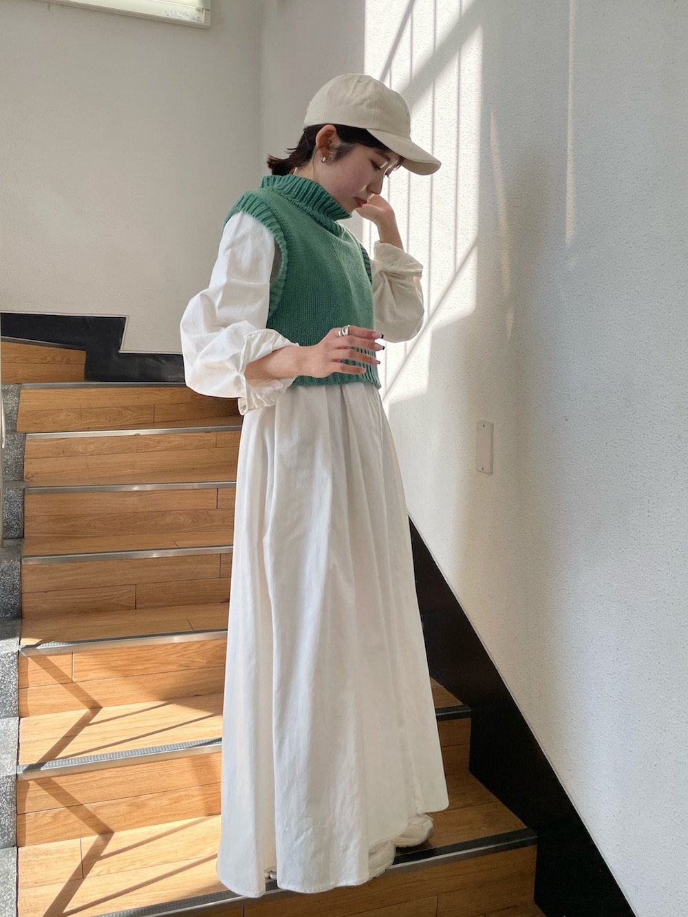 グリーン系のワンピース、ホワイト系のキャップを着用したレディースの春コーディネートの3枚目の写真