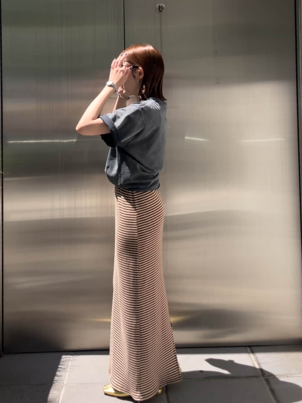 ブラウン系のワンピース、ゴールド系のパンプス、グレー系のTシャツ/カットソーを着用したレディースの夏コーディネートの3枚目の写真