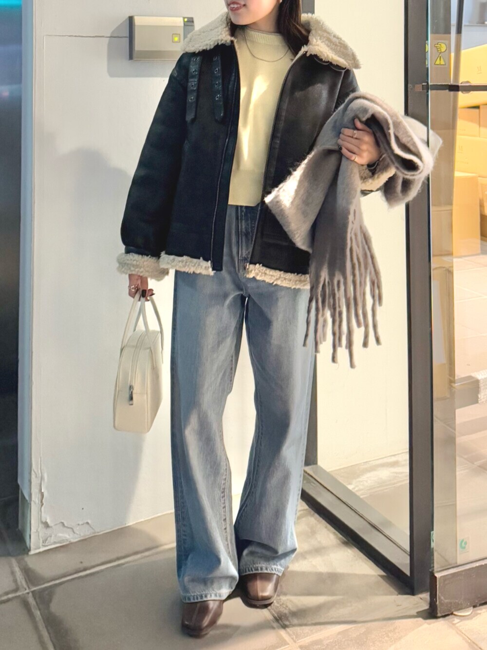 ブラウン系のブーツ、ブルー系のデニムパンツ、イエロー系のニット/セーターを着用したレディースの冬コーディネートの2枚目の写真