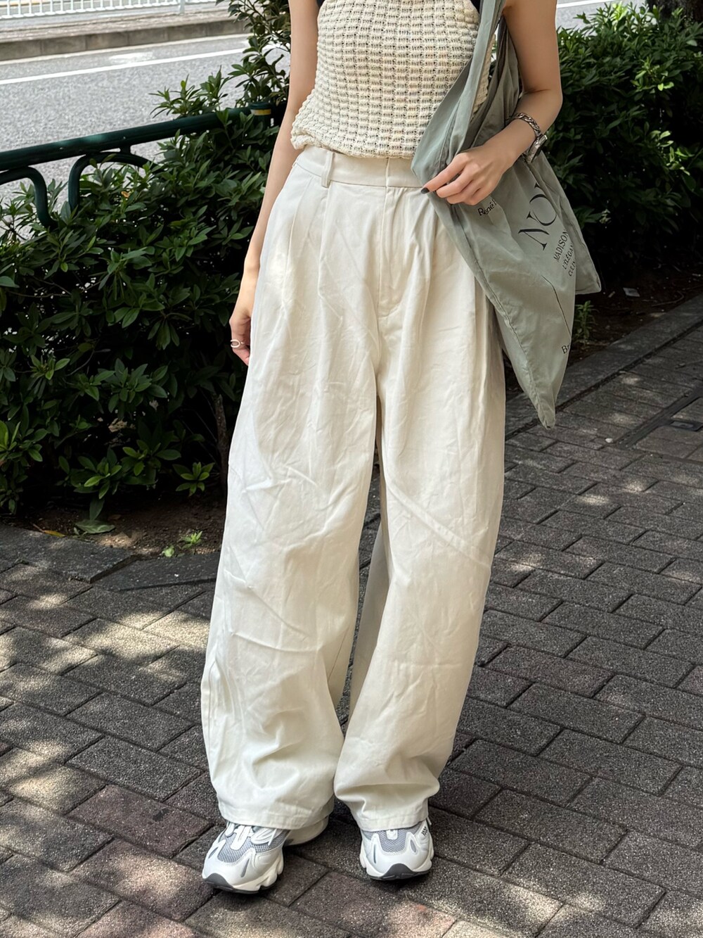 ホワイト系のチノパンツ、グリーン系のトートバッグ、ホワイト系のタンクトップを着用したレディースの夏コーディネートの5枚目の写真