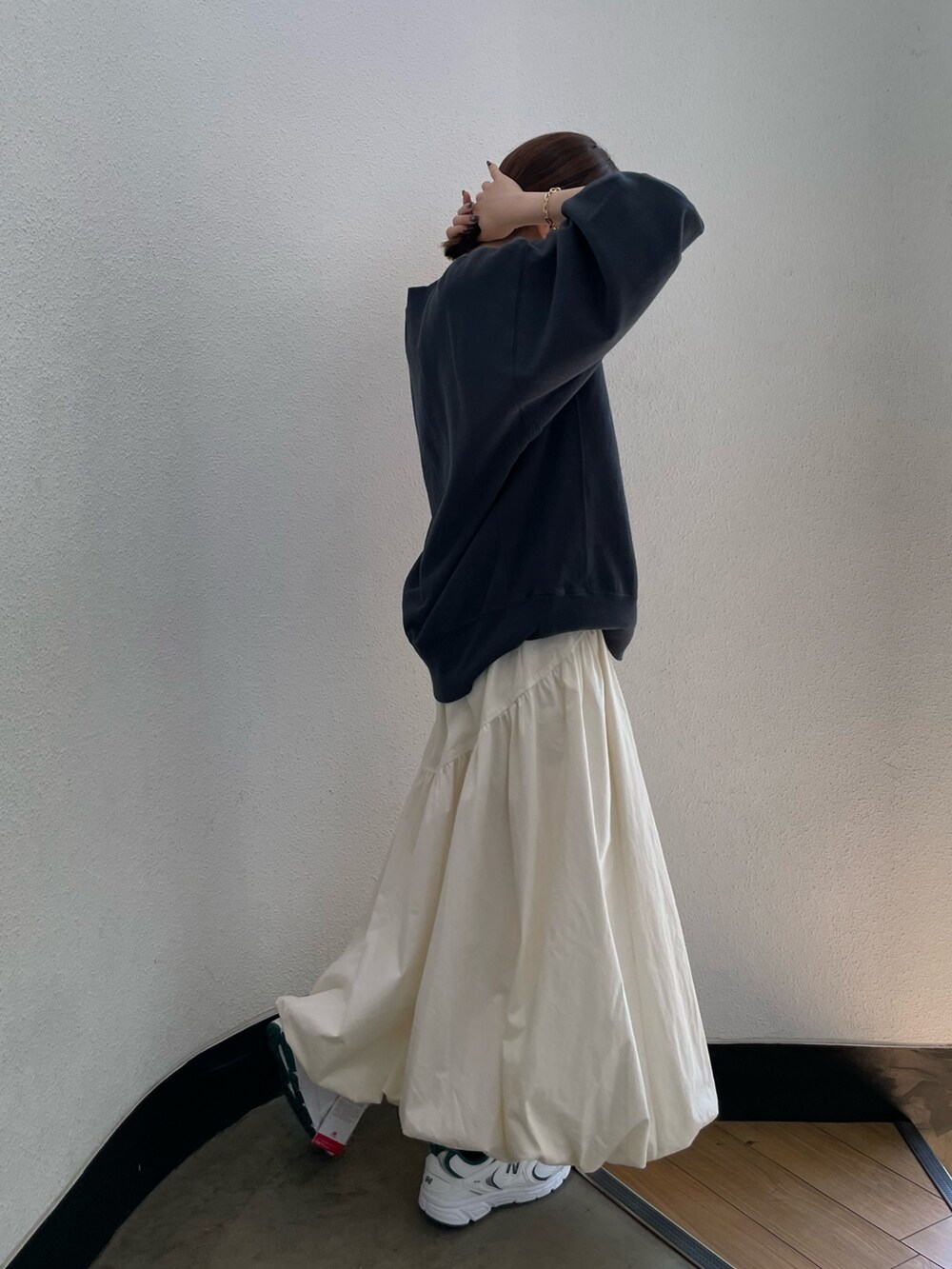 グレー系のスウェット、ホワイト系のスカート、グリーン系のスニーカーを着用したレディースの夏コーディネートの2枚目の写真