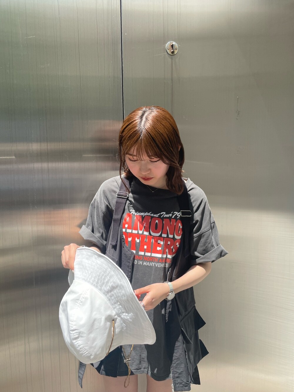 グレー系のTシャツ/カットソー、ブラック系のベスト、ホワイト系のハットを着用したレディースの春コーディネートの7枚目の写真