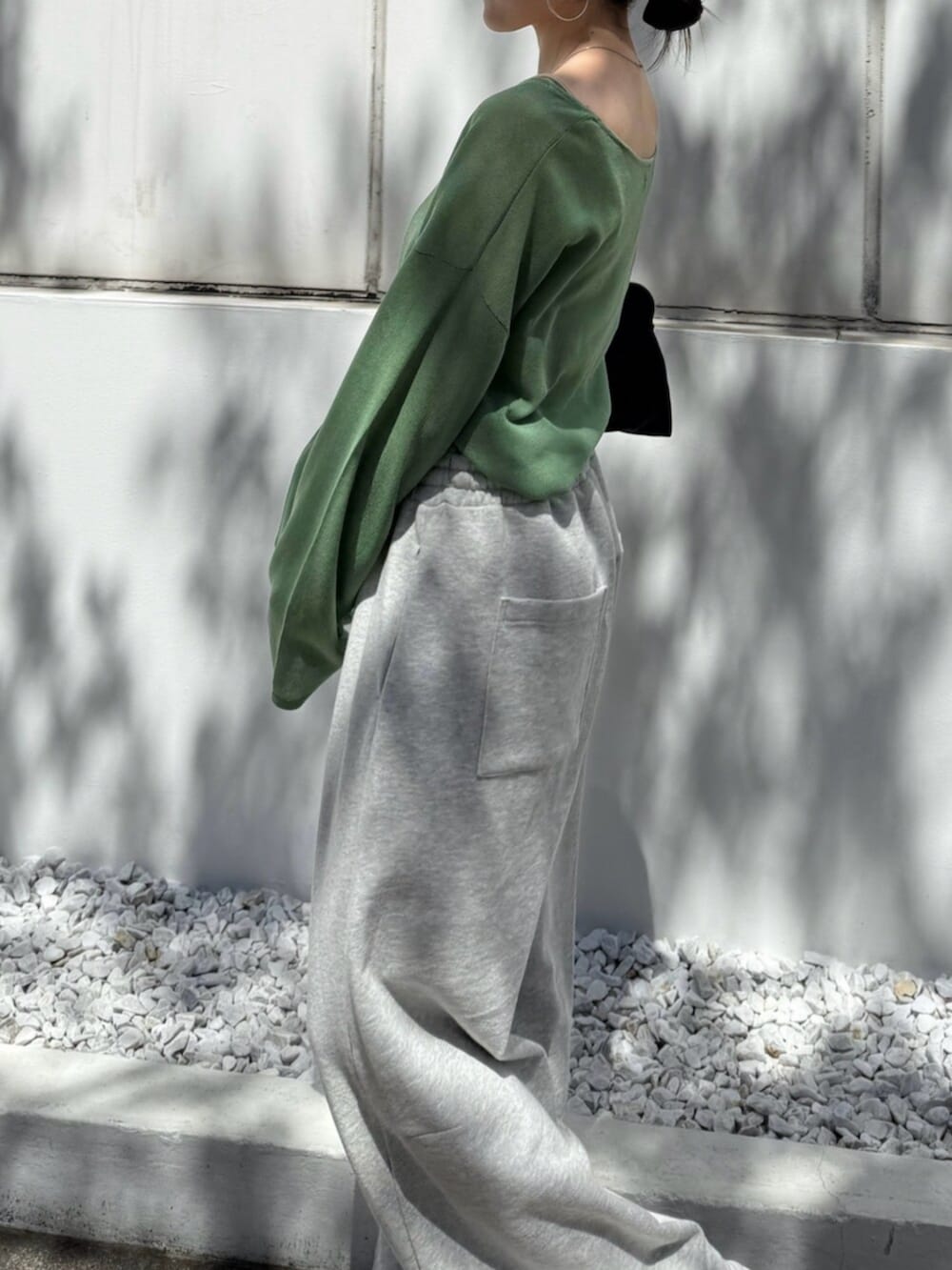 グレー系のスウェットパンツ、ブラック系のハンドバッグ、グリーン系のニット/セーターを着用したレディースの春コーディネートの3枚目の写真