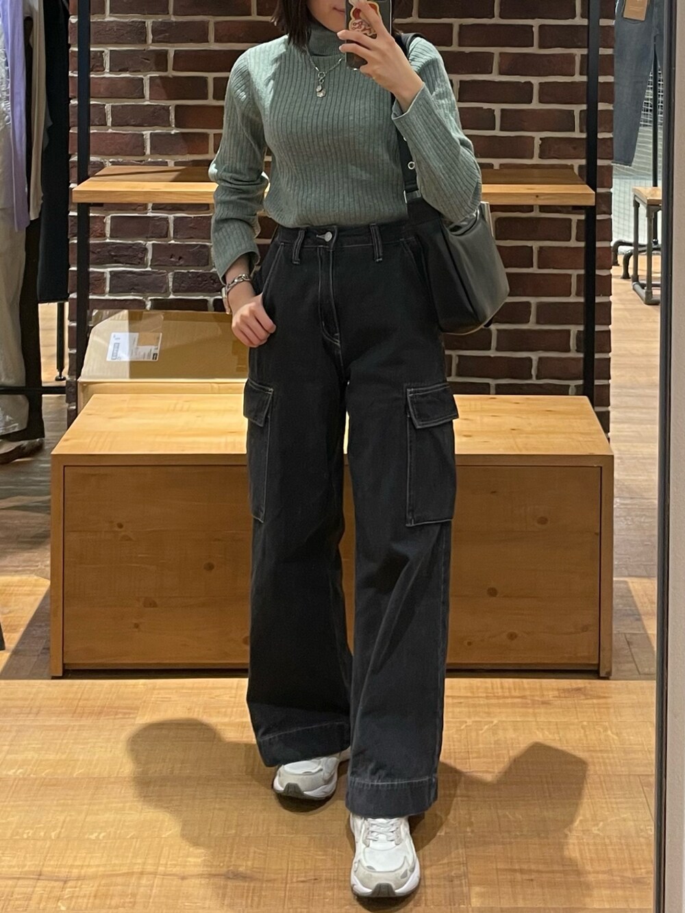 グリーン系のニット/セーター、ブラック系のショルダーバッグ、ブラック系のデニムパンツを着用したレディースの冬コーディネートの2枚目の写真