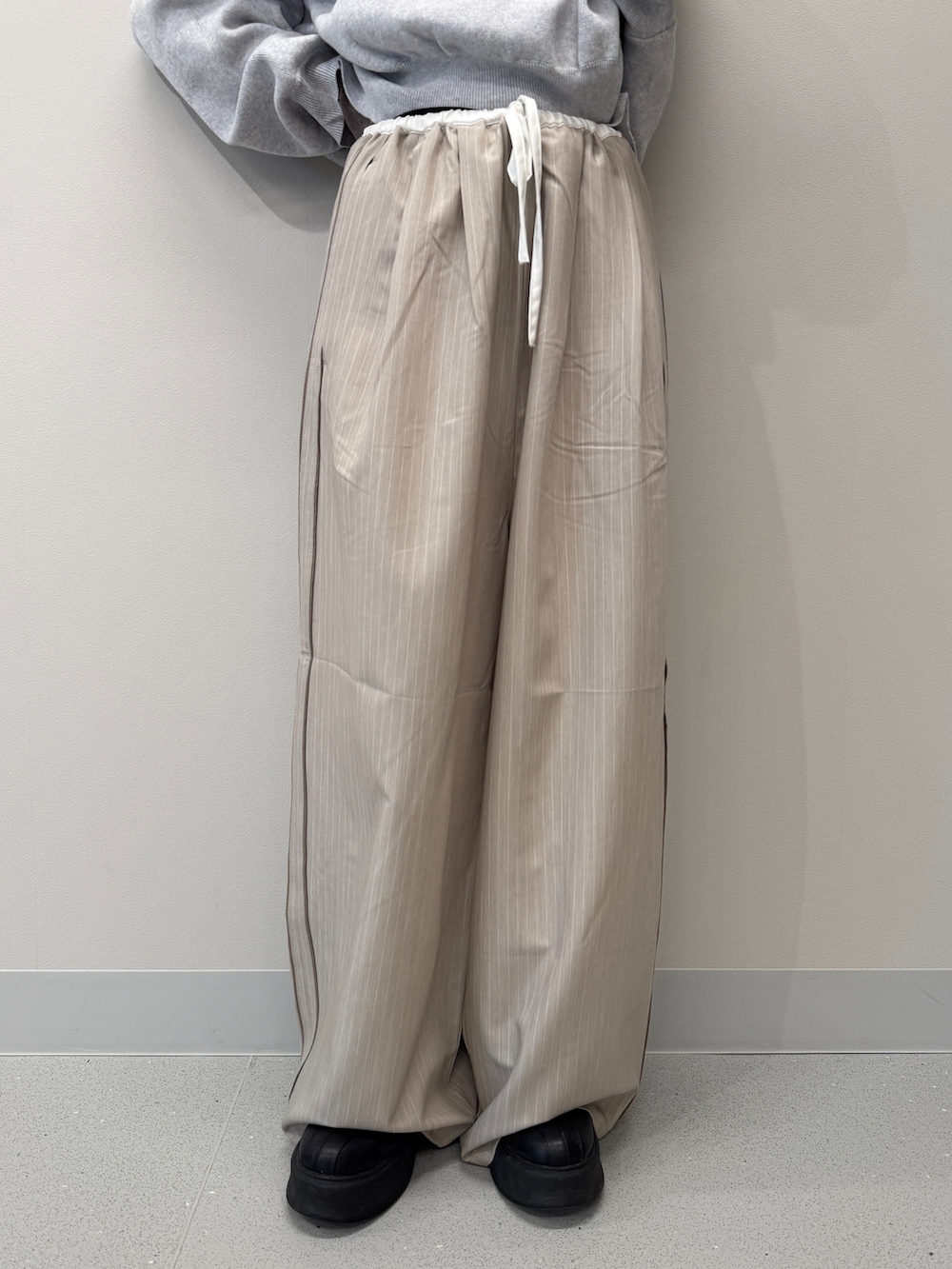 ベージュ系のその他パンツ、グレー系のニット/セーター、ブラック系のブーツを着用したレディースの冬コーディネートの4枚目の写真