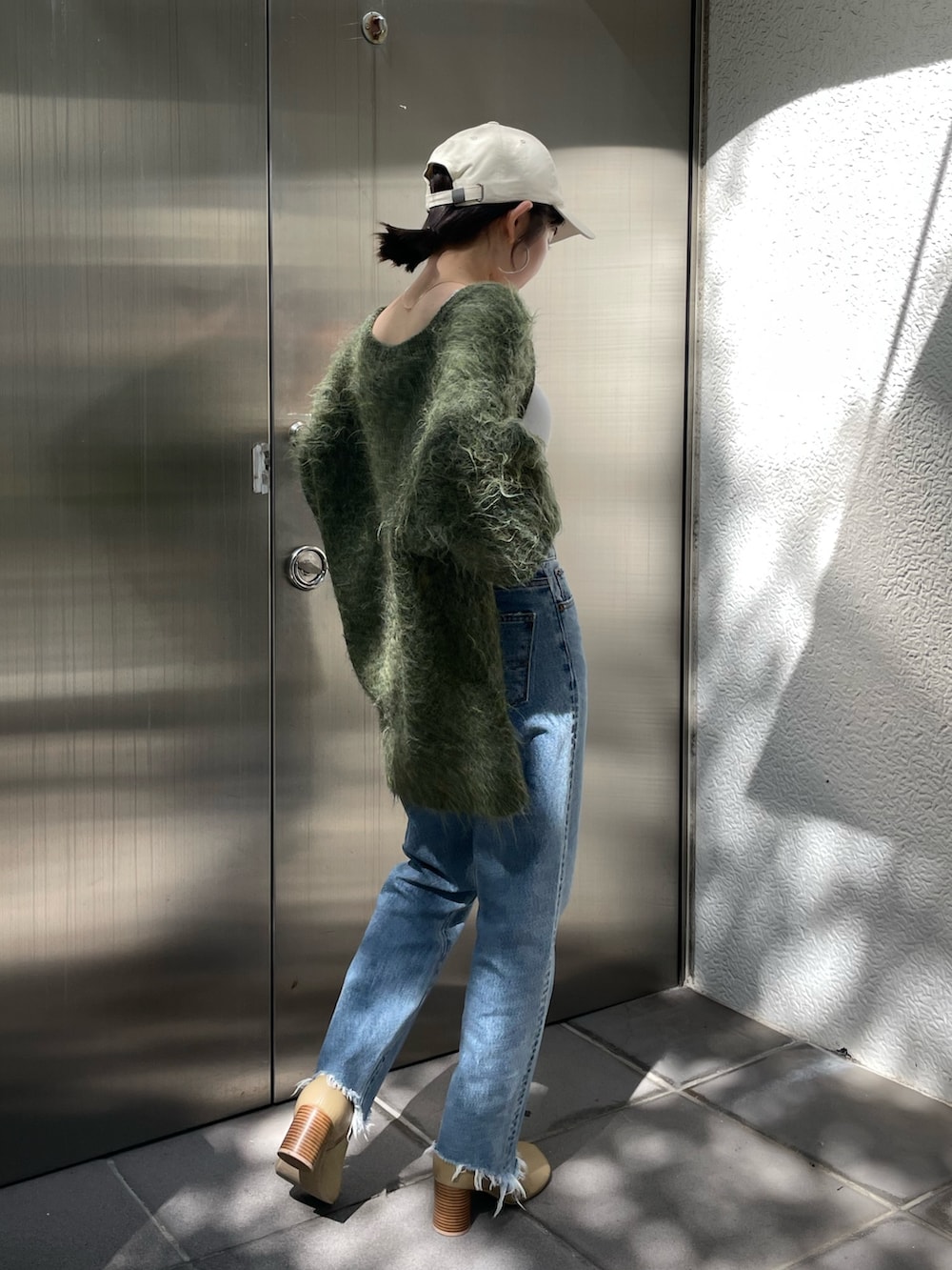 グリーン系のカーディガン/ボレロ、ベージュ系のブーツ、ブルー系のデニムパンツを着用したレディースの秋コーディネートの3枚目の写真