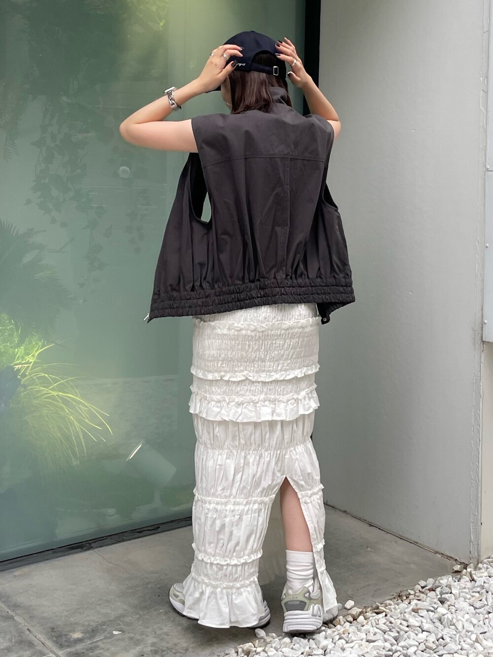 グレー系のベスト、ホワイト系のスカート、ブルー系のキャップを着用したレディースの夏コーディネートの5枚目の写真