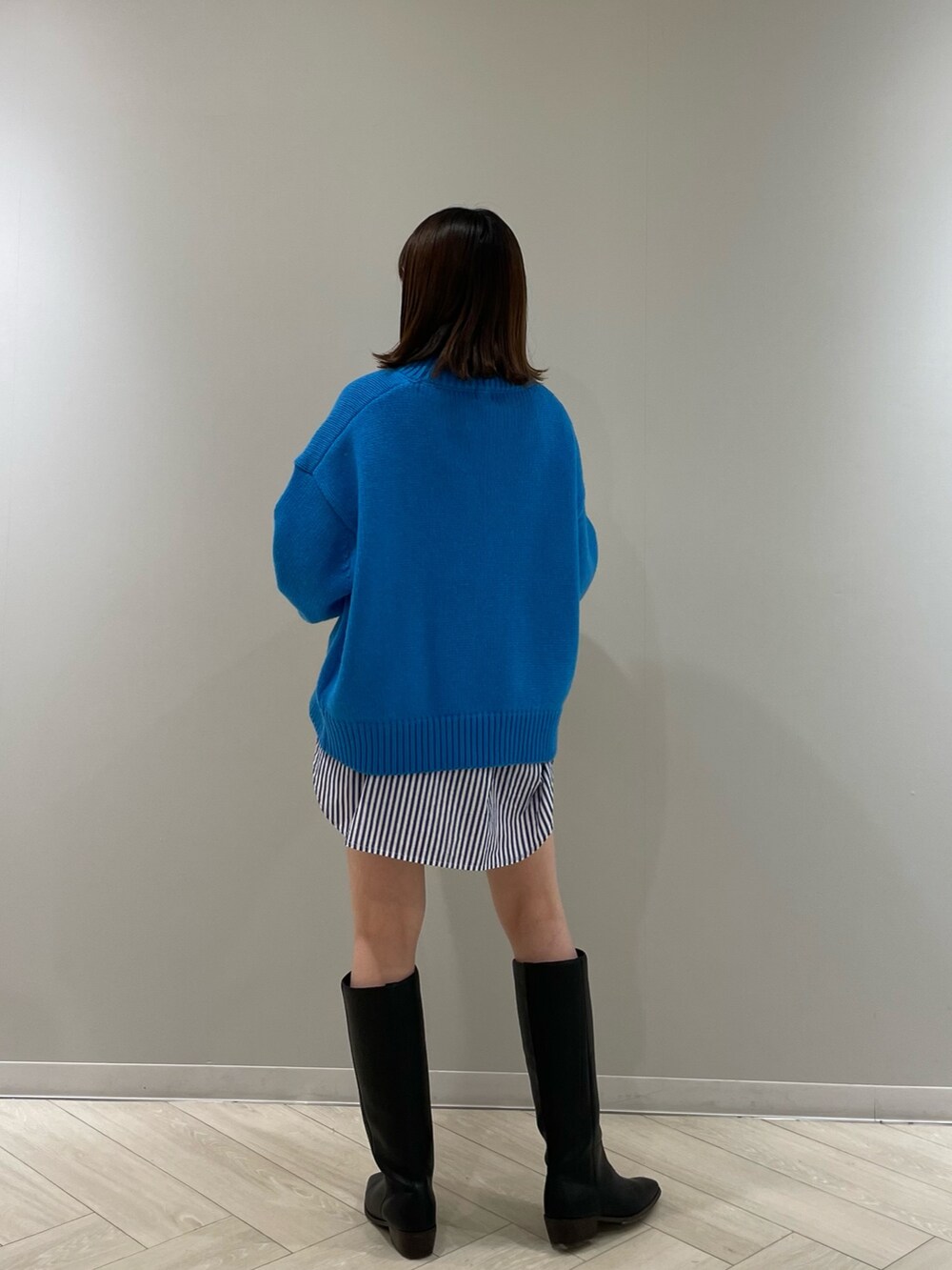 ブルー系のニット/セーター、イエロー系のクラッチバッグ、ブラック系のシューズを着用したレディースの冬コーディネートの6枚目の写真