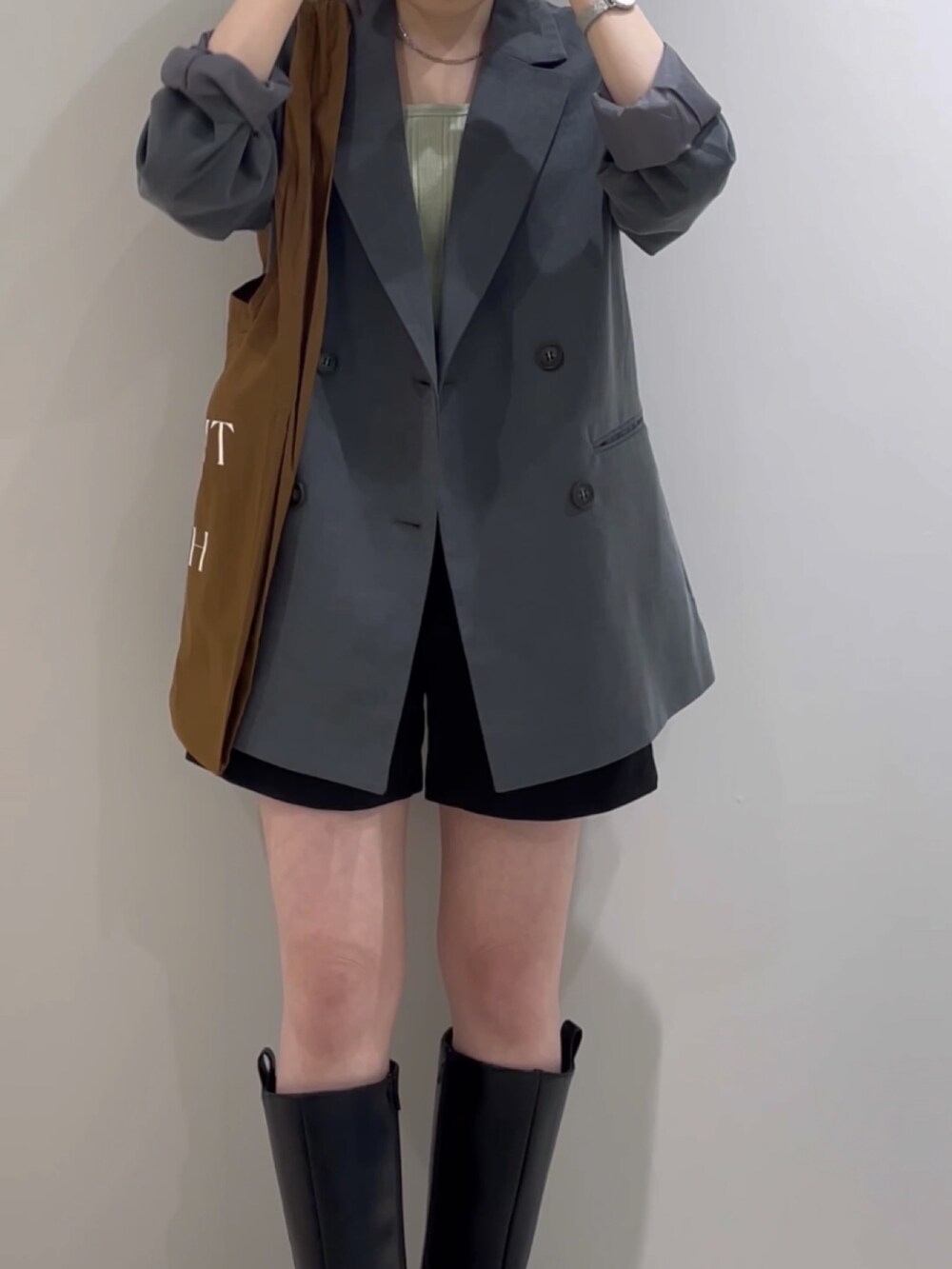 グレー系のテーラードジャケット、グリーン系のタンクトップ、ブラウン系のエコバッグ/サブバッグを着用したレディースの冬コーディネートの5枚目の写真