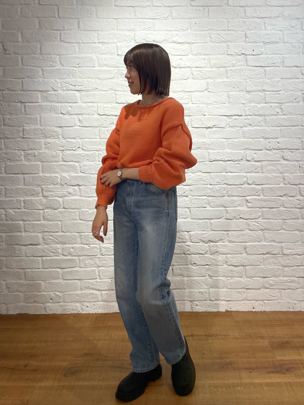 オレンジ系のニット/セーター、ブルー系のデニムパンツ、ブラック系のブーツを着用したレディースの冬コーディネートの2枚目の写真
