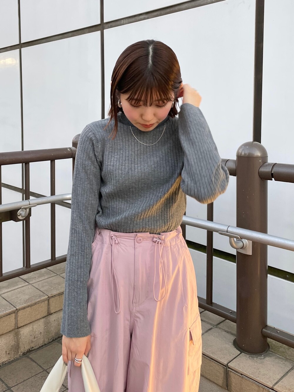 ピンク系のカーゴパンツ、ホワイト系のハンドバッグ、グレー系のニット/セーターを着用したレディースの冬コーディネートの3枚目の写真