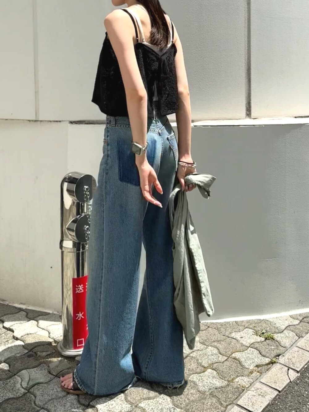 ブラック系のサンダル、グリーン系のトートバッグ、ブルー系のデニムパンツを着用したレディースの夏コーディネートの4枚目の写真