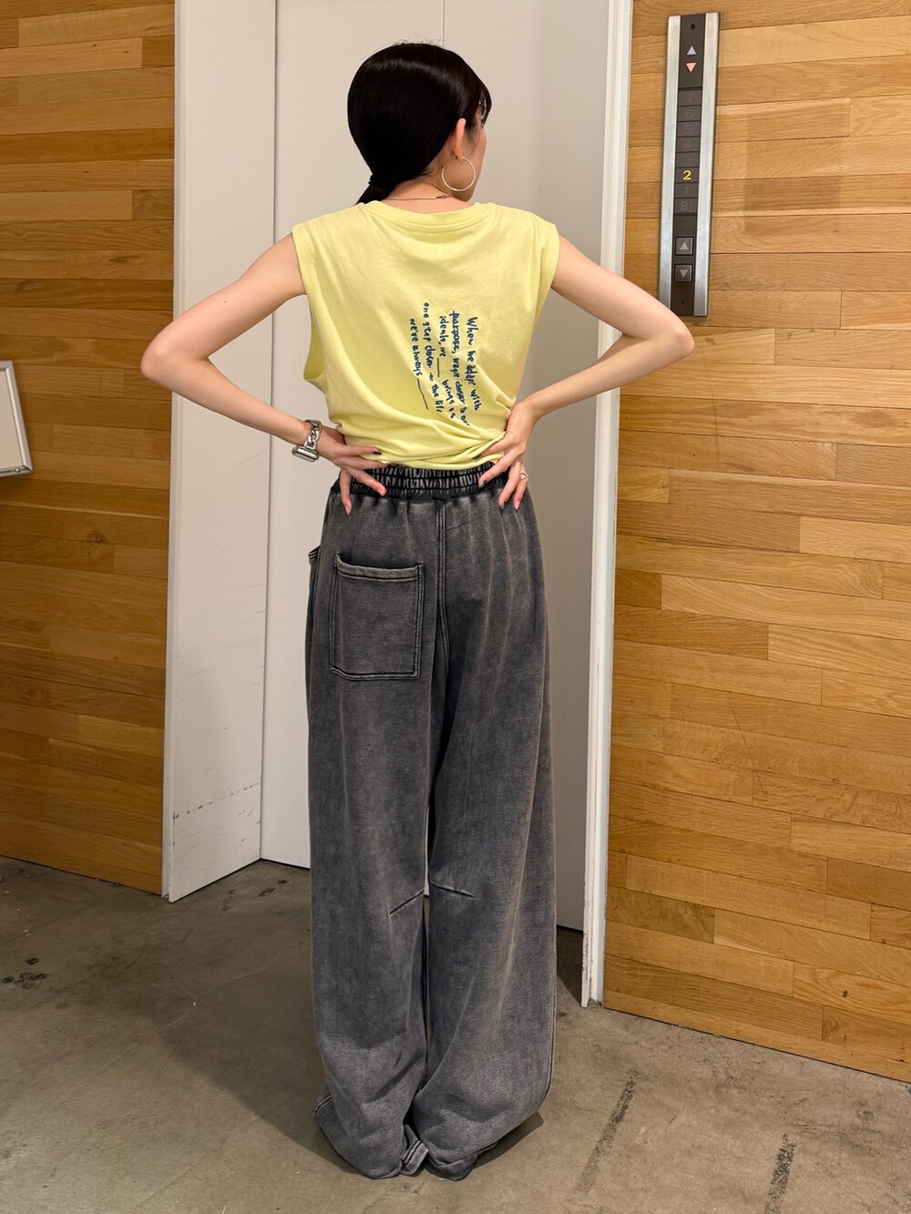 グレー系のスウェットパンツ、イエロー系のタンクトップ、ホワイト系のサンダルを着用したレディースの夏コーディネートの4枚目の写真