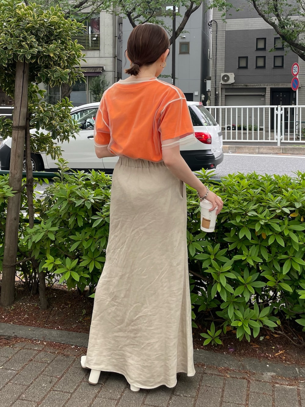 ホワイト系のサンダル、オレンジ系のTシャツ/カットソー、ベージュ系のスカートを着用したレディースの春コーディネートの3枚目の写真