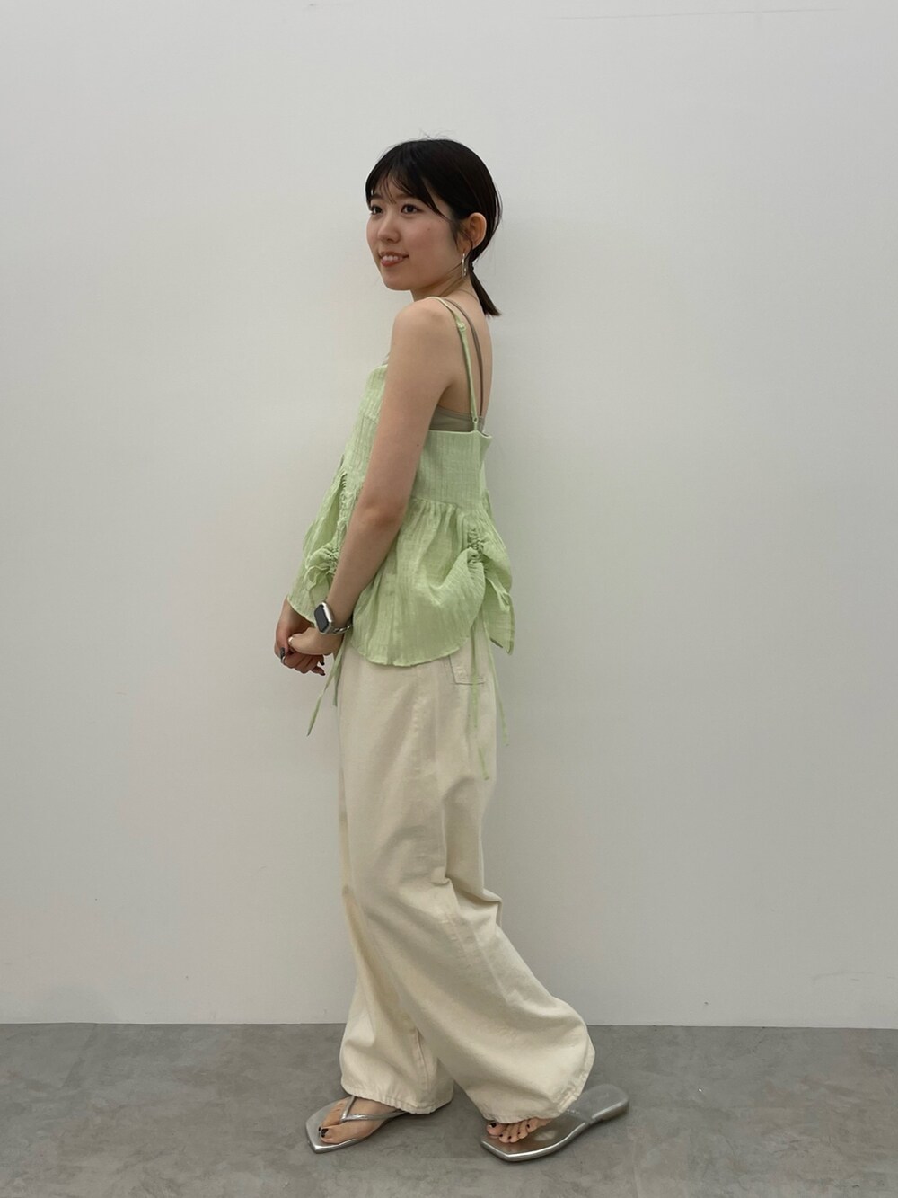 グレー系のキャミソール、ホワイト系のデニムパンツ、シルバー系のサンダルを着用したレディースの春コーディネートの3枚目の写真