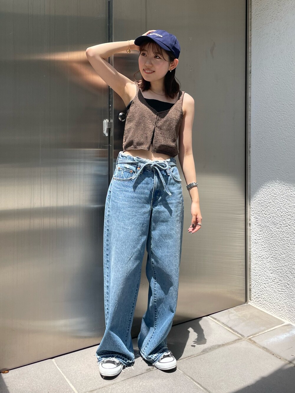 ブラウン系のベスト、ブルー系のデニムパンツ、ブルー系のキャップを着用したレディースの夏コーディネートの2枚目の写真