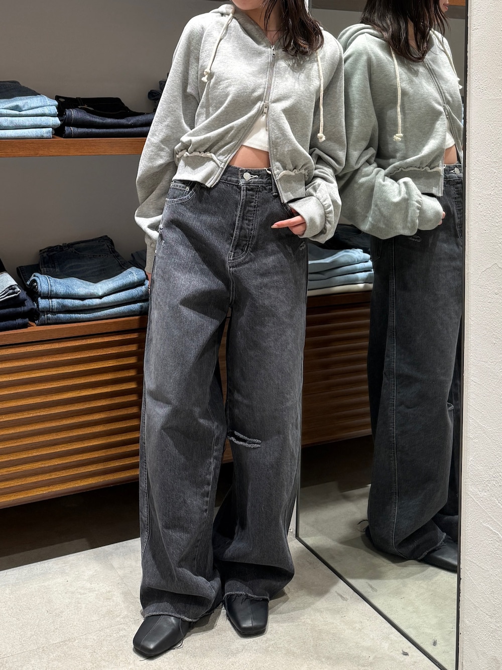 ブラック系のサンダル、グレー系のパーカー、ブラック系のデニムパンツを着用したレディースの春コーディネートの6枚目の写真