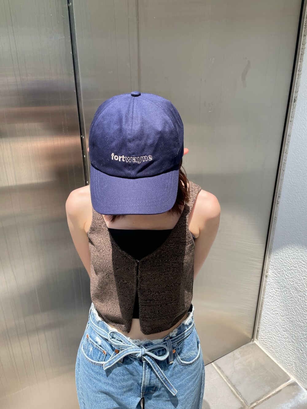 ブラウン系のベスト、ブルー系のデニムパンツ、ブルー系のキャップを着用したレディースの夏コーディネートの7枚目の写真